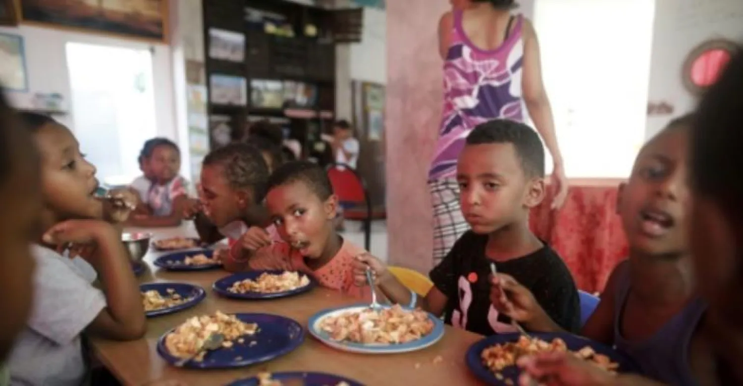 Children of Eritrean migrants eat lunch at a makeshift kindergarten in south Tel Aviv on September 4, 2017. Their families live in limbo in Israel, fearing deportation. By MENAHEM KAHANA (AFP/File)