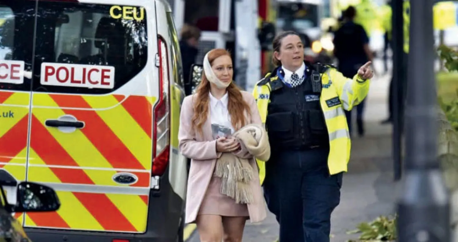 شرطية بريطانية تصطحب إحدى المصابات في حادث الهجوم على محطة «بارسونز غرين» (أ.ب)