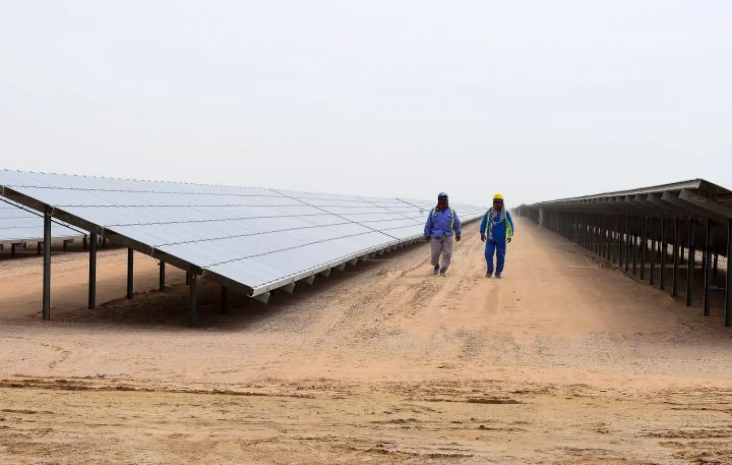 Employees walk past solar panels at the Mohammed bin Rashid Al-Maktoum Solar Park on March 20, 2017, in Dubai. AFP PHOTO / STRINGER 