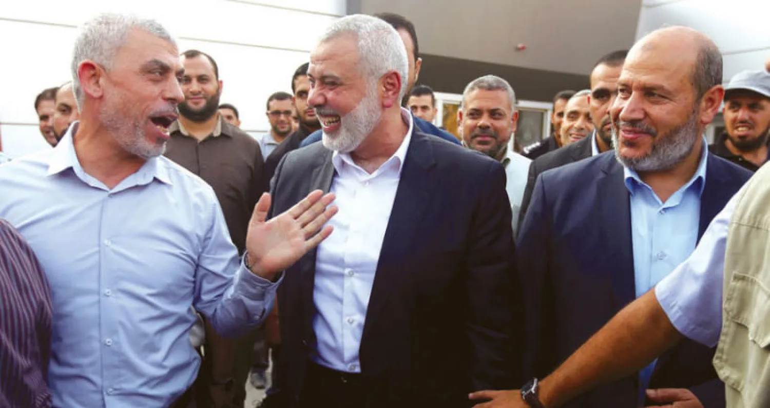 إسماعيل هنية (وسط) وإلى يمينه يحيى السنوار يتبادلان الحديث لحظة وصولهما إلى معبر رفح (رويترز)