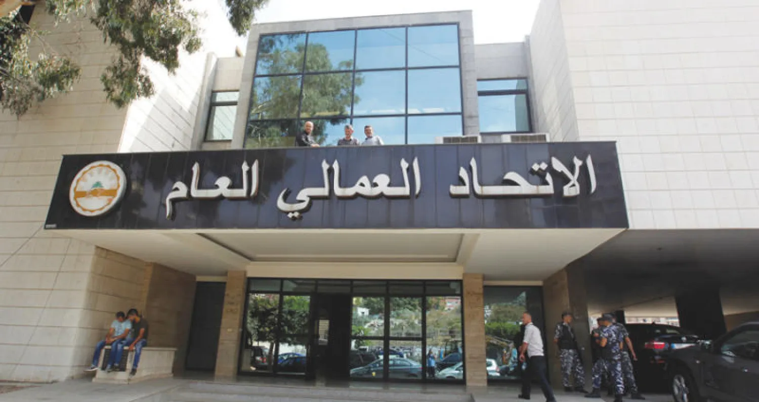 نقابيون تسلقوا واجهة الاتحاد العمالي العام في اليوم الأول لإضراب القطاع العام في لبنان أمس (رويترز)