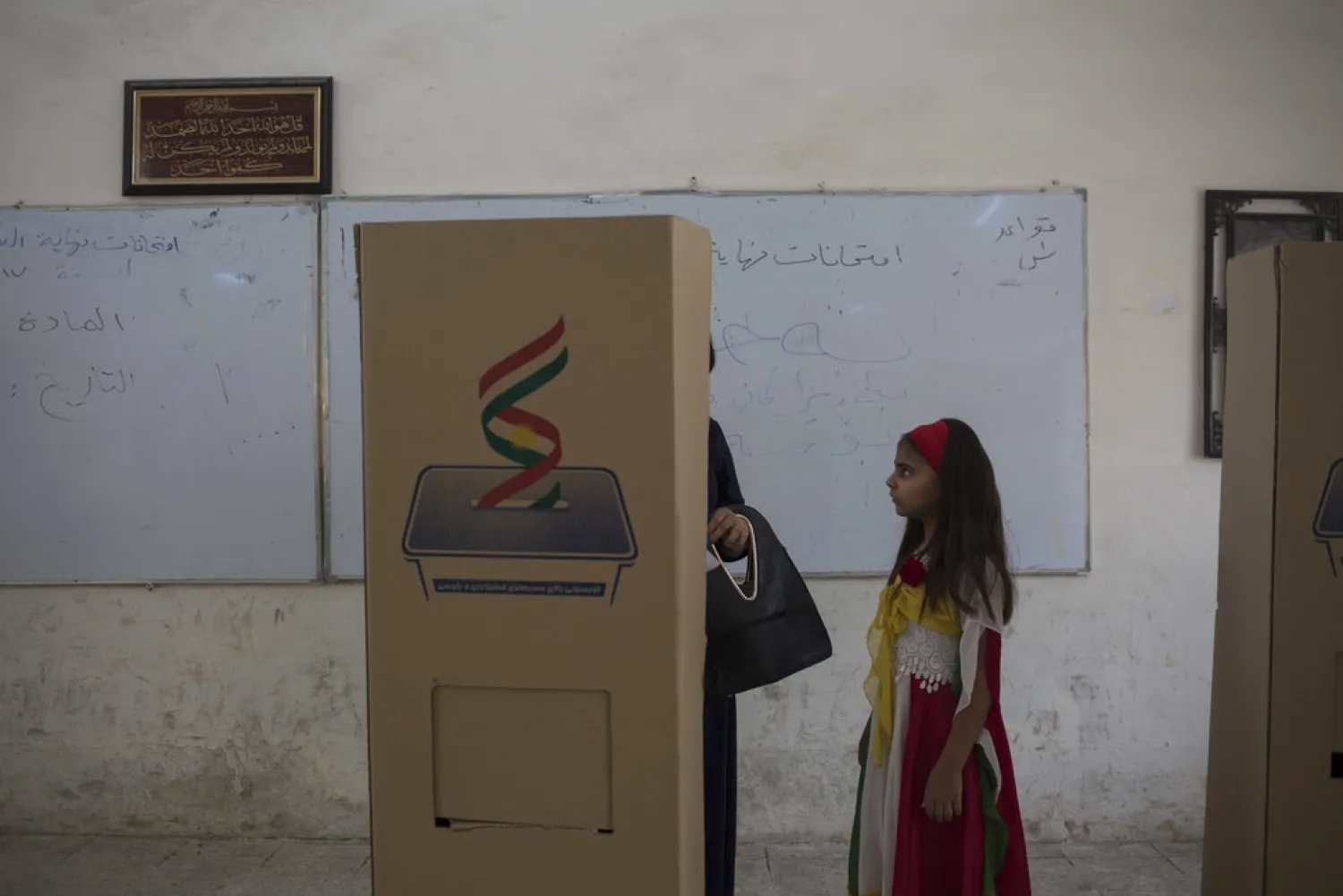 A girl dressed in the colors of the Kurdish flag looks at her mother as she votes inside the boot for Kurdish independence in the city of Kirkuk, Monday Sept. 25, 2017. (AP Photo/Bram Janssen) 