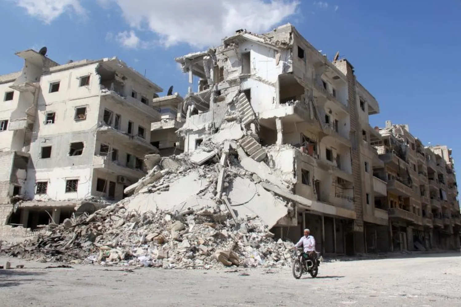 سكان وأفراد من الدفاع المدني «الخوذ البيضاء» يبحثون عن الضحايا وسط أنقاض في مدينة حريم شمال غرب محافظة ادلب (أ.ف.ب)