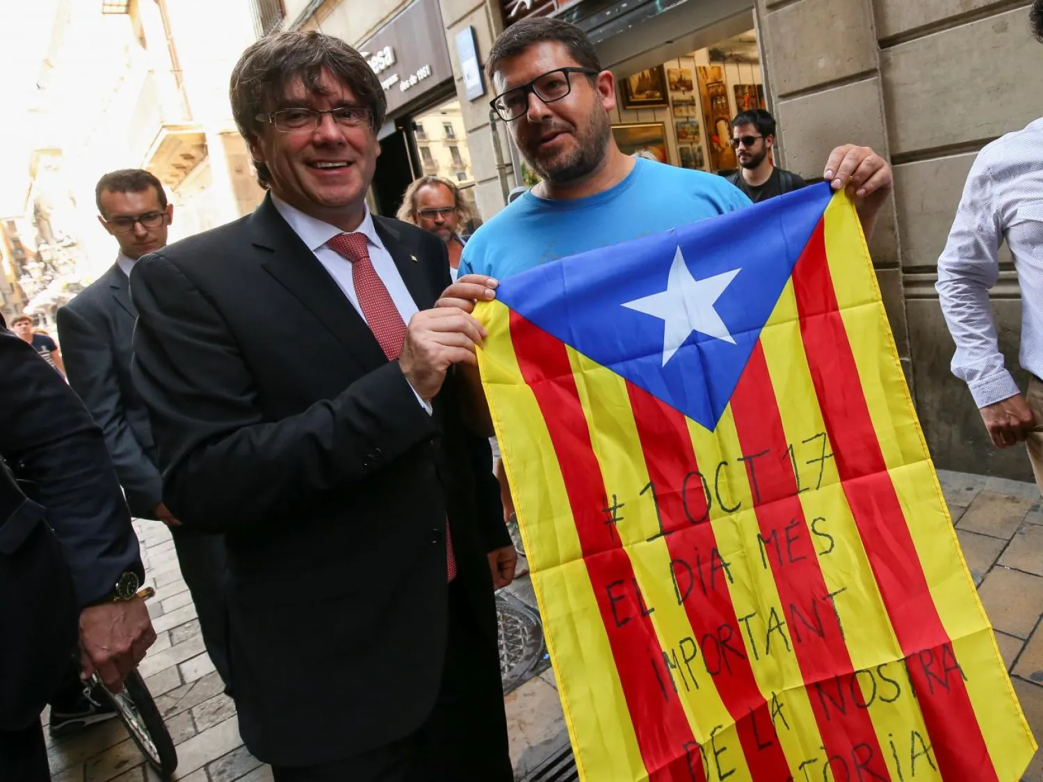 Catalonia's regional President Carles Puigdemont poses next to a pro-independence supporter with a Catalan Estelada flag showing the date for which the regional government called for a referendum on a split from Spain outside the Palau de la Generalitat, the regional government headquarters, in Barcelona, Spain, June 9, 2017. Reuters