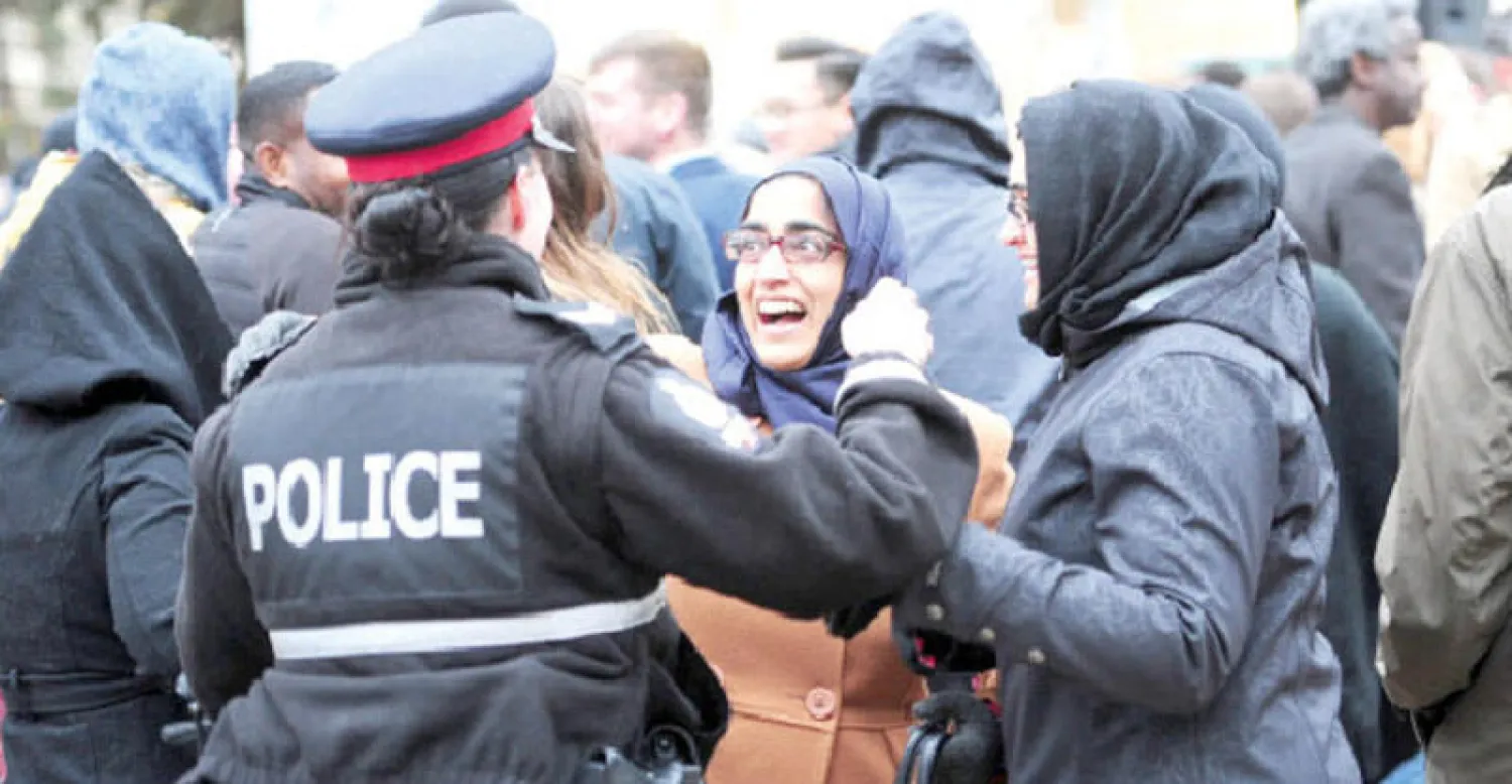 سيدة مسلمة تتحدث مع ضابطة شرطة كندية خلال وقفة للترحم على ضحايا الهجوم الإرهابي في إدمنتون أمس (رويترز)