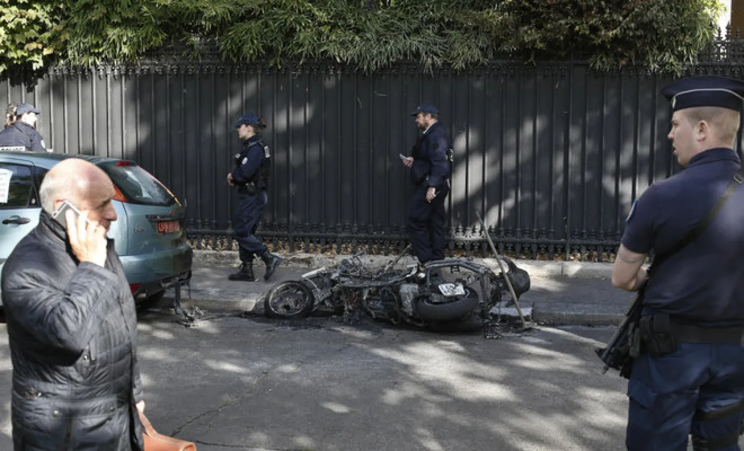 Police officers stand next to a burnt scooter outside the office of Jordan's military attache in Paris CREDIT: THIBAULT CAMUS/AP