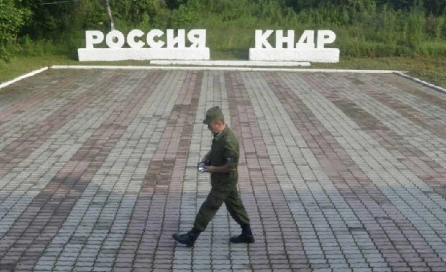 A guard walks along a platform past signs, which read "Russia" (L) and "DPRK"(Democratic People's Republic of Korea), at the border crossing between Russia and North Korea in the settlement of Tumangan, North Korea July 18, 2014. REUTERS/Yuri Maltsev/File Photo