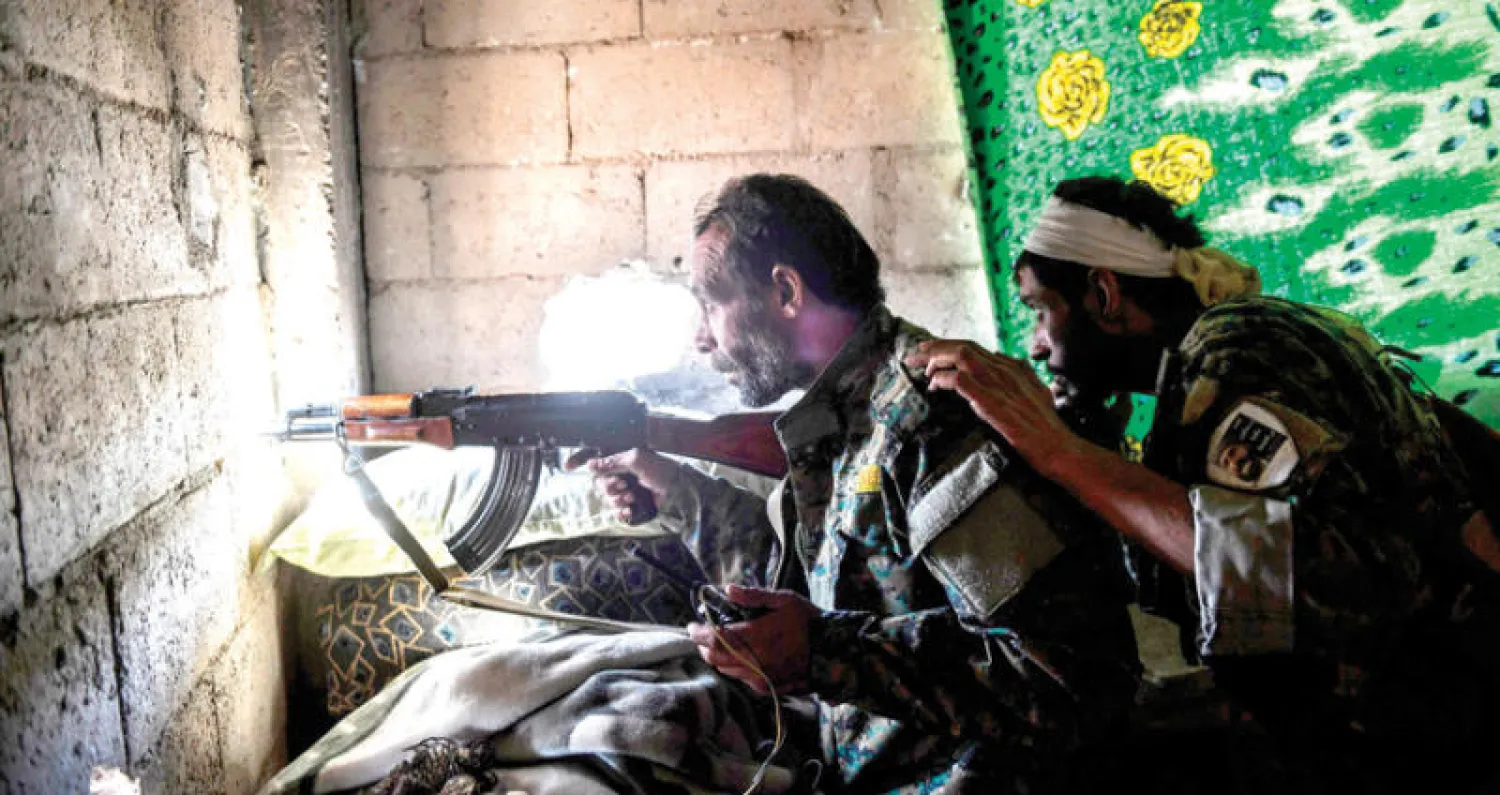 عنصران من قوات سوريا الديمقراطية يصوبان سلاحهما نحو عناصر {داعش} في الرقة أمس (أ.ف.ب)