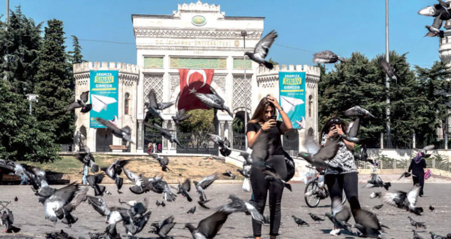 طيور الحمام قرب مواطنين وسياح أمام بوابة جامع إسطنبول (أ.ف.ب)