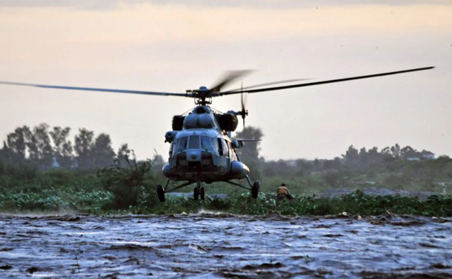 An Indian Air Force Mi-17 helicopter hovers above the Tawi river during a rescue sortie to pick up two men (R) stranded during floods in the outskirts of Jammu on August 14, 2013: AFP