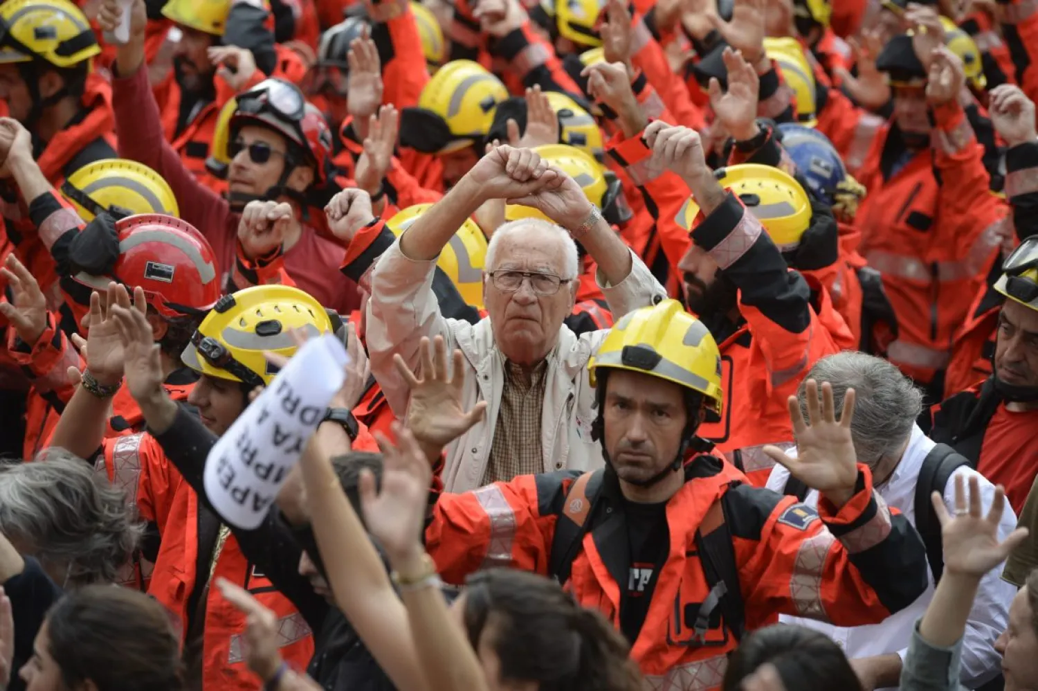 Protesters joined by firefighters raise their hands as they gather during a general strike in Barcelona called by Catalan unions on October 3, 2017. AFP PHOTO / Josep LAGO