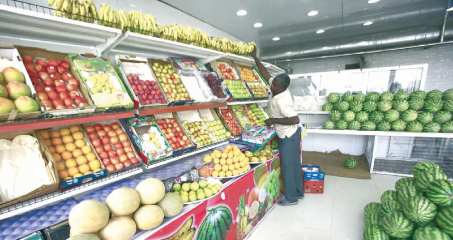 بائع خضار وفواكه يعمل في محله في مدينة أم درمان (أ.ف.ب)