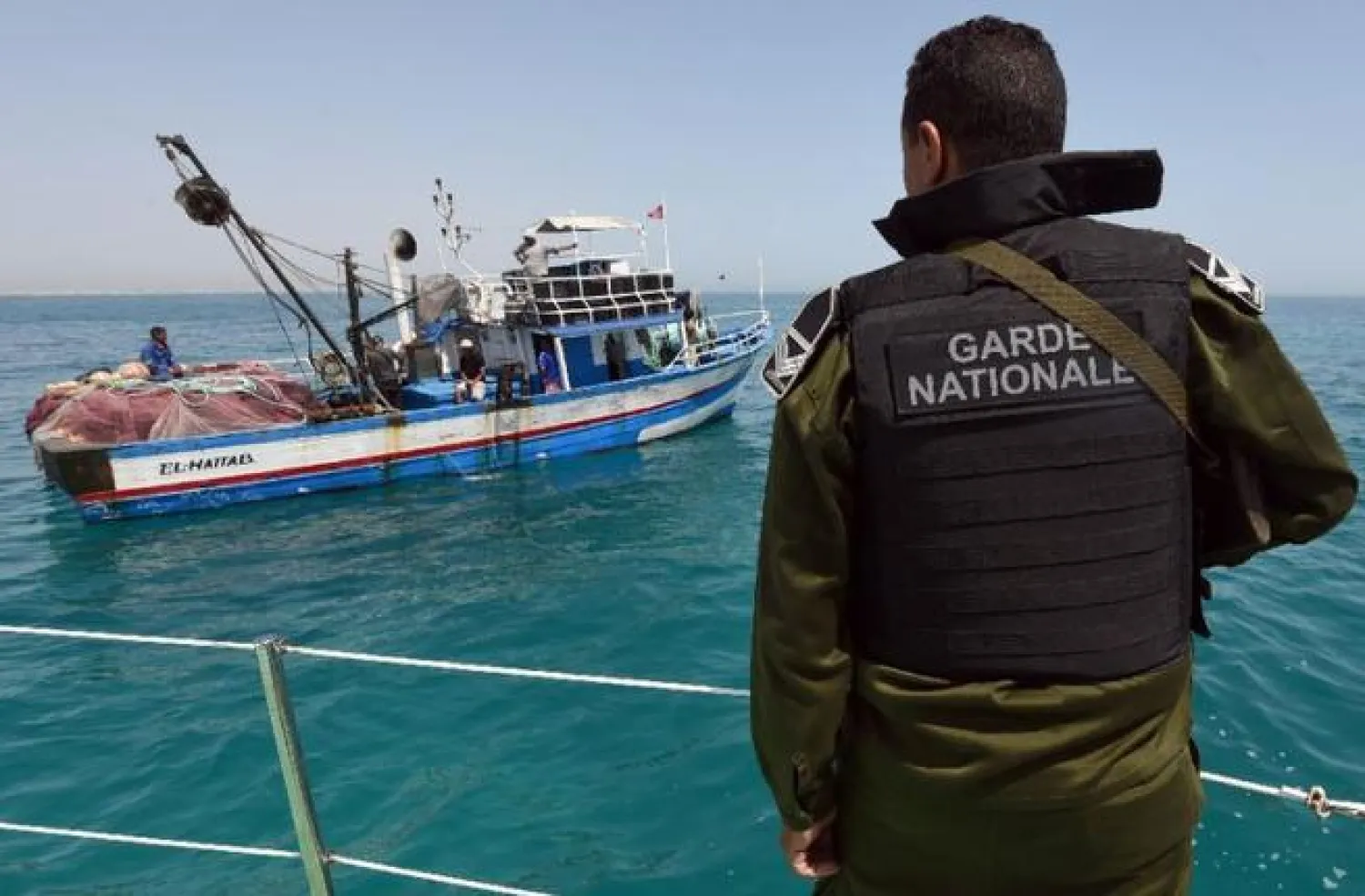 A member of the Tunisian Coast Guard observes a fishing boat. (AFP/File)
