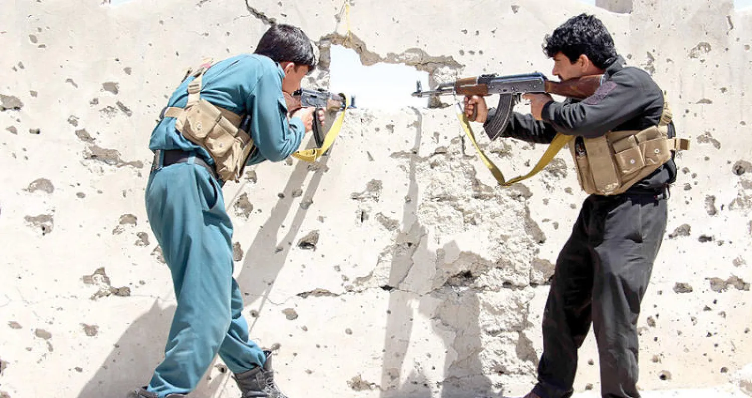 جنديان أفغانيان يتبادلان إطلاق النار مع متشددين على الخطوط الأمامية في منطقة ند علي بولاية هلمند أول من أمس (إ.ب.أ)