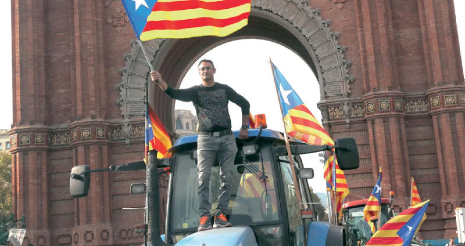 كاتالوني يلوح خلال مظاهرة في برشلونة أمس بعلم الإقليم (إ.ب.أ)... وفي الإطار رئيس الإقليم كارليس بوتشيمون مخاطباً برلمانه (رويترز)