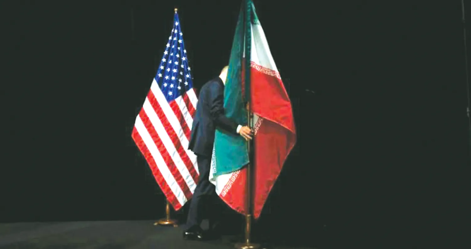 أحد الموظفين يقوم بإزالة العلمين الأميركي والإيراني بعد صورة جماعية لوزراء خارجية إيران والمجموعة الدولية 5+1 عقب إعلان الاتفاق النووي في مركز فيينا الدولي منتصف يوليو 2015 (رويترز