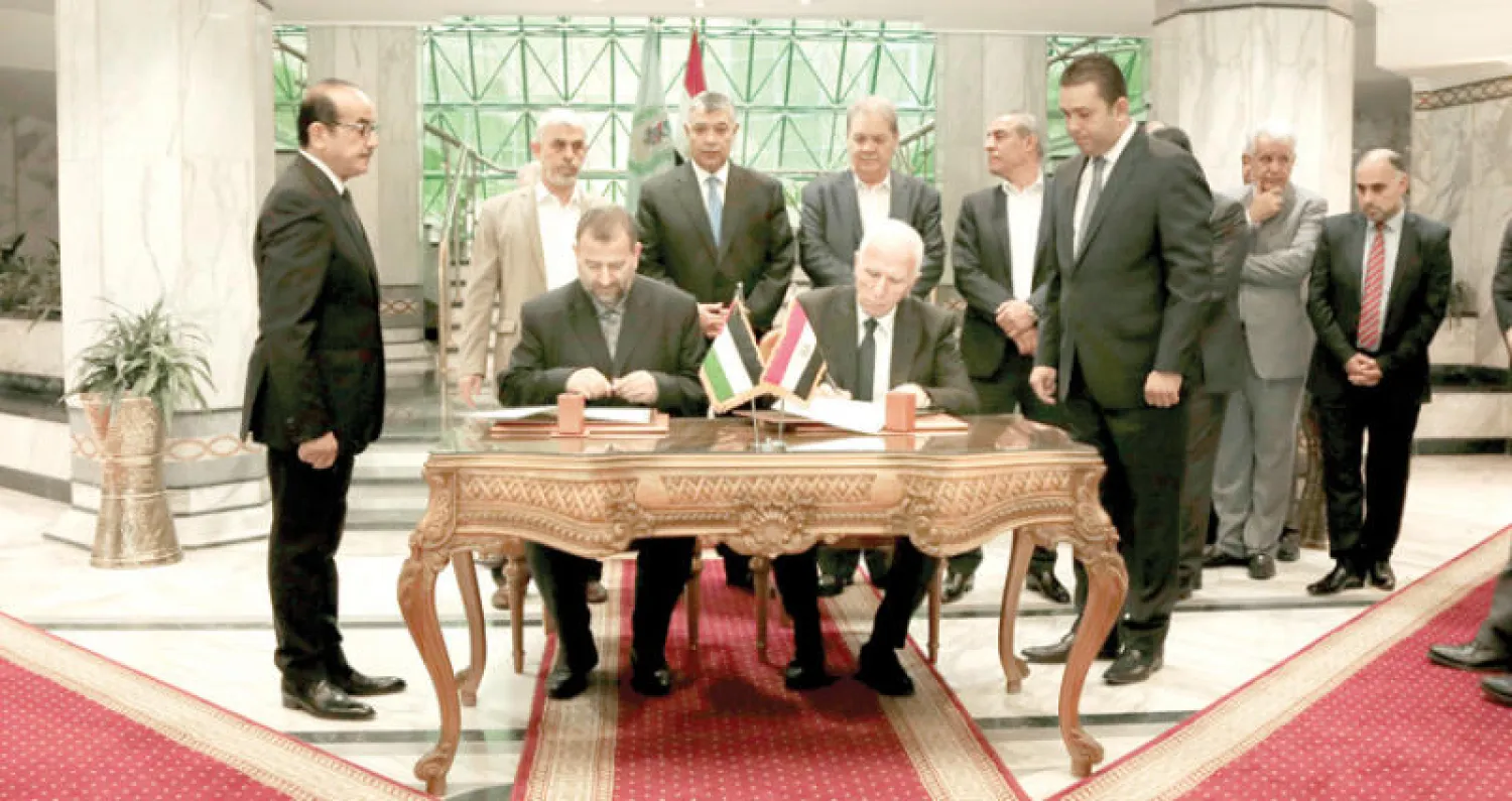 رئيسا وفدي «فتح» عزام الأحمد (يمين) و«حماس» صالح العاروري خلال توقيعهما الاتفاق في القاهرة أمس (أ.ب)