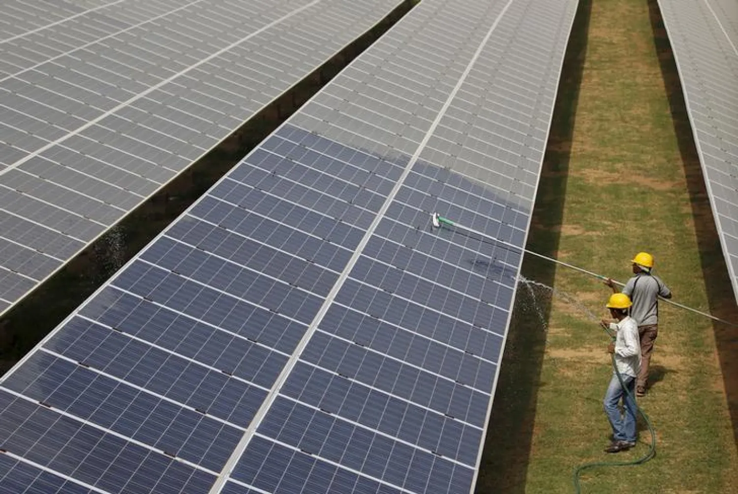 Workers clean photovoltaic panels inside a solar power plant in Gujarat, India, in this July 2, 2015 file photo. REUTERS/Amit Dave/Files