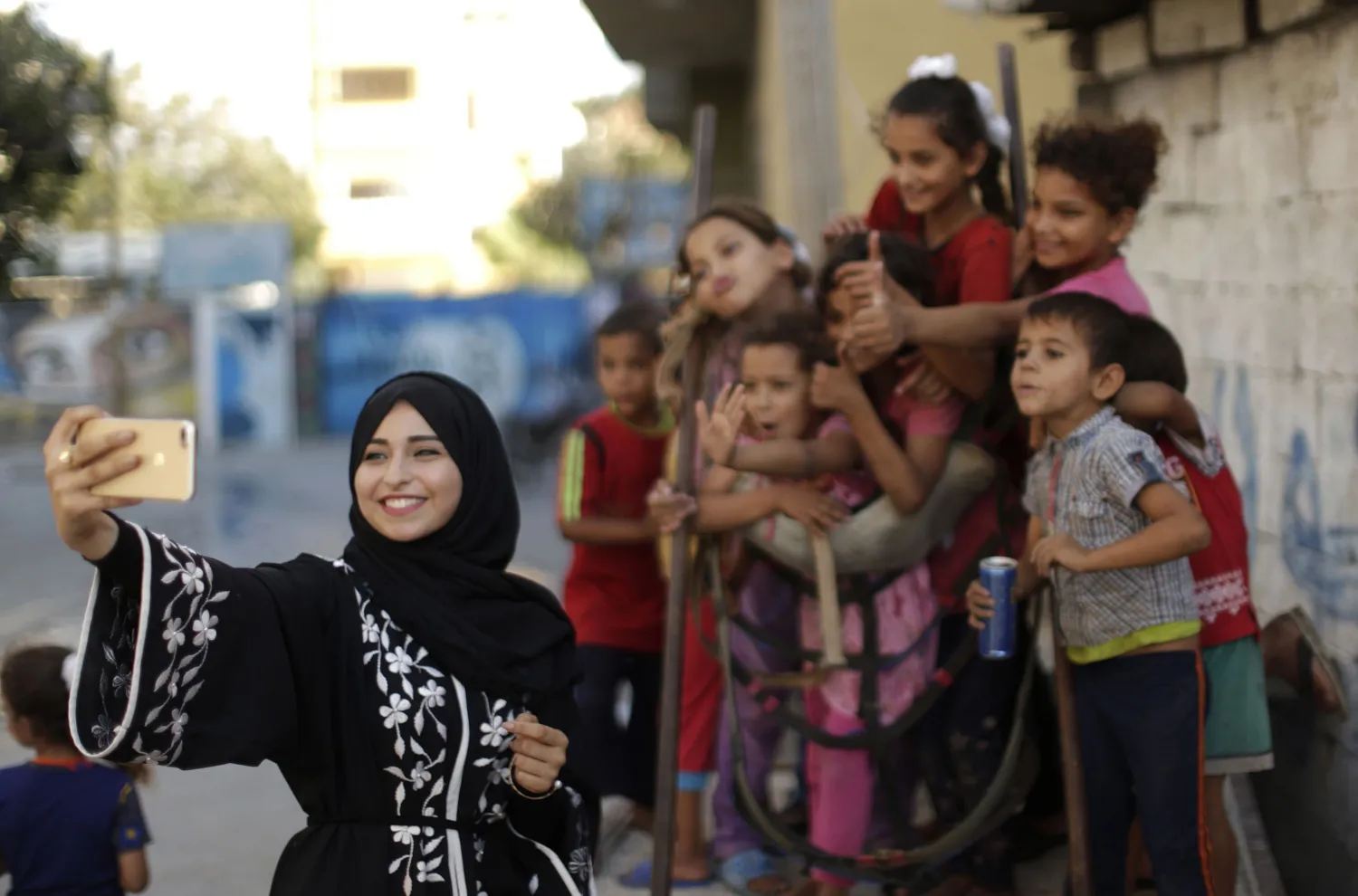 Palestinian Fatma Abu Musabah uses her mobile phone to take pictures of children for her social media account in Deir al-Balah in the central Gaza strip on September 17, 2017. MAHMUD HAMS / AFP 