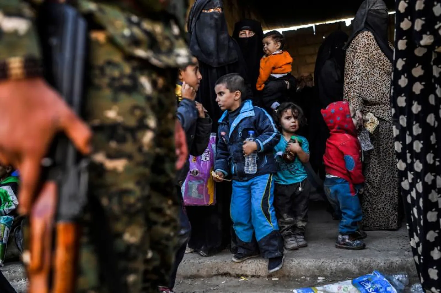 نساء وأطفال يتجمعون على الجبهة الغربية بعد فرارهم من مركز الرقة (أ.ف.ب)