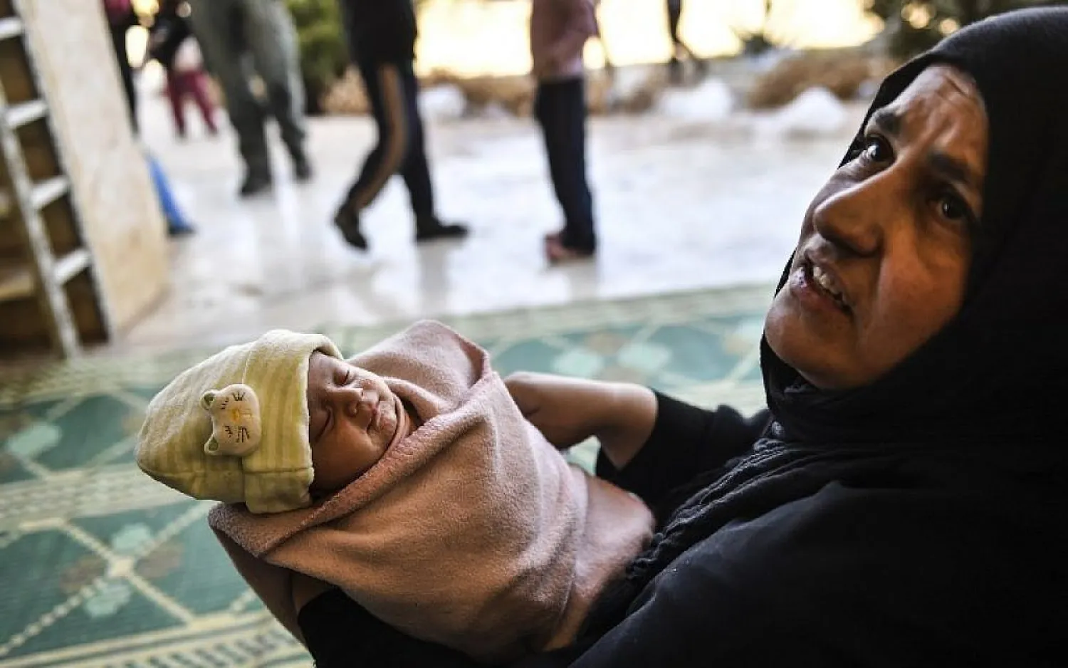 A woman, who along with members of her family was used as human shields by ISIS group fighters, holds a new born baby after fleeing from the center of Raqqa, Syria, October 6, 2017. (AFP//BULENT KILIC)