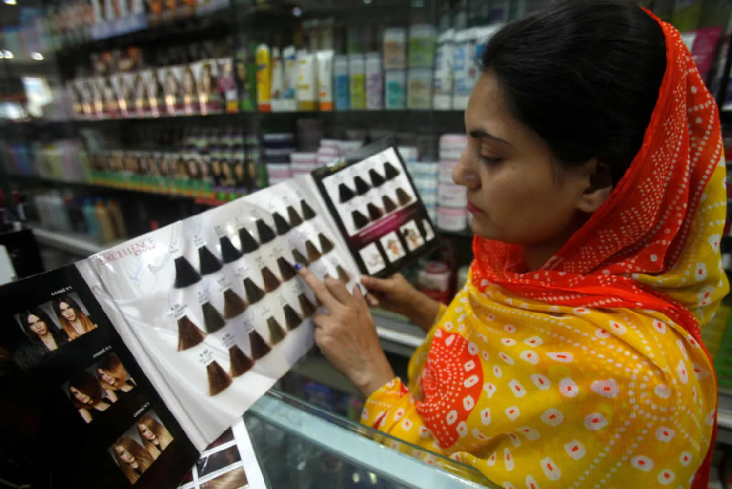 سيدة من بيشاور تختار صبغة لشعرها من أحد المحلات (رويترز)