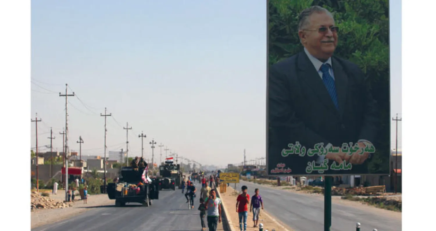 صورة عملاقة للرئيس الراحل جلال طالباني بجانب طريق يسلكها جنود عراقيون خلال تقدمهم نحو وسط مدينة كركوك أمس (أ.ف.ب)... وفي الإطار شرطيون عراقيون يدوسون العلم الكردي في قاعدة سابقة للقوات الكردية في كركوك (إ.ب.أ)