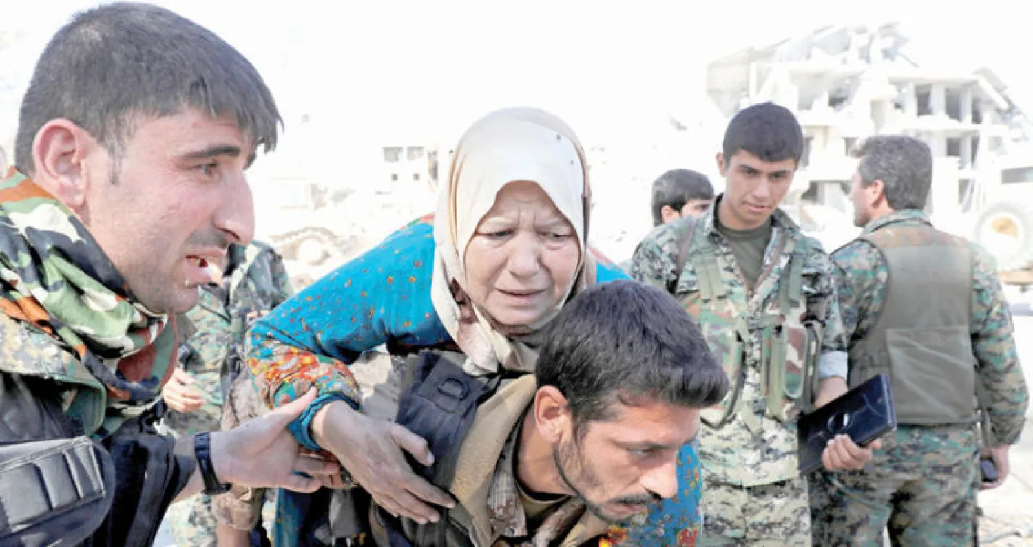 نقل امرأة من ملعب الرقة حيث كانت مع مدنيين آخرين رهائن لـ«داعش» (رويترز)