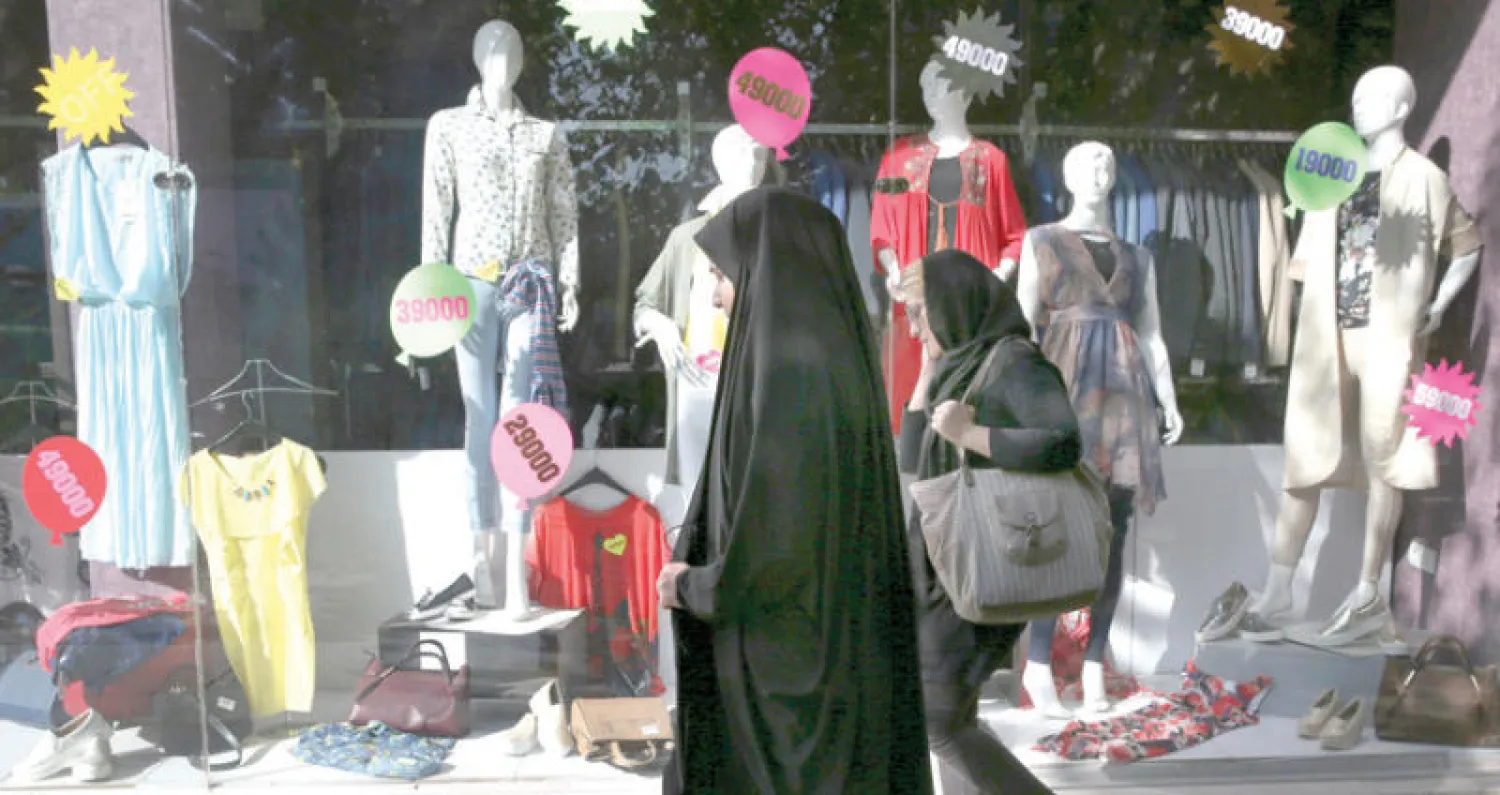 إيرانيتان تمران أمام محل لبيع الملابس في طهران (أ.ب)