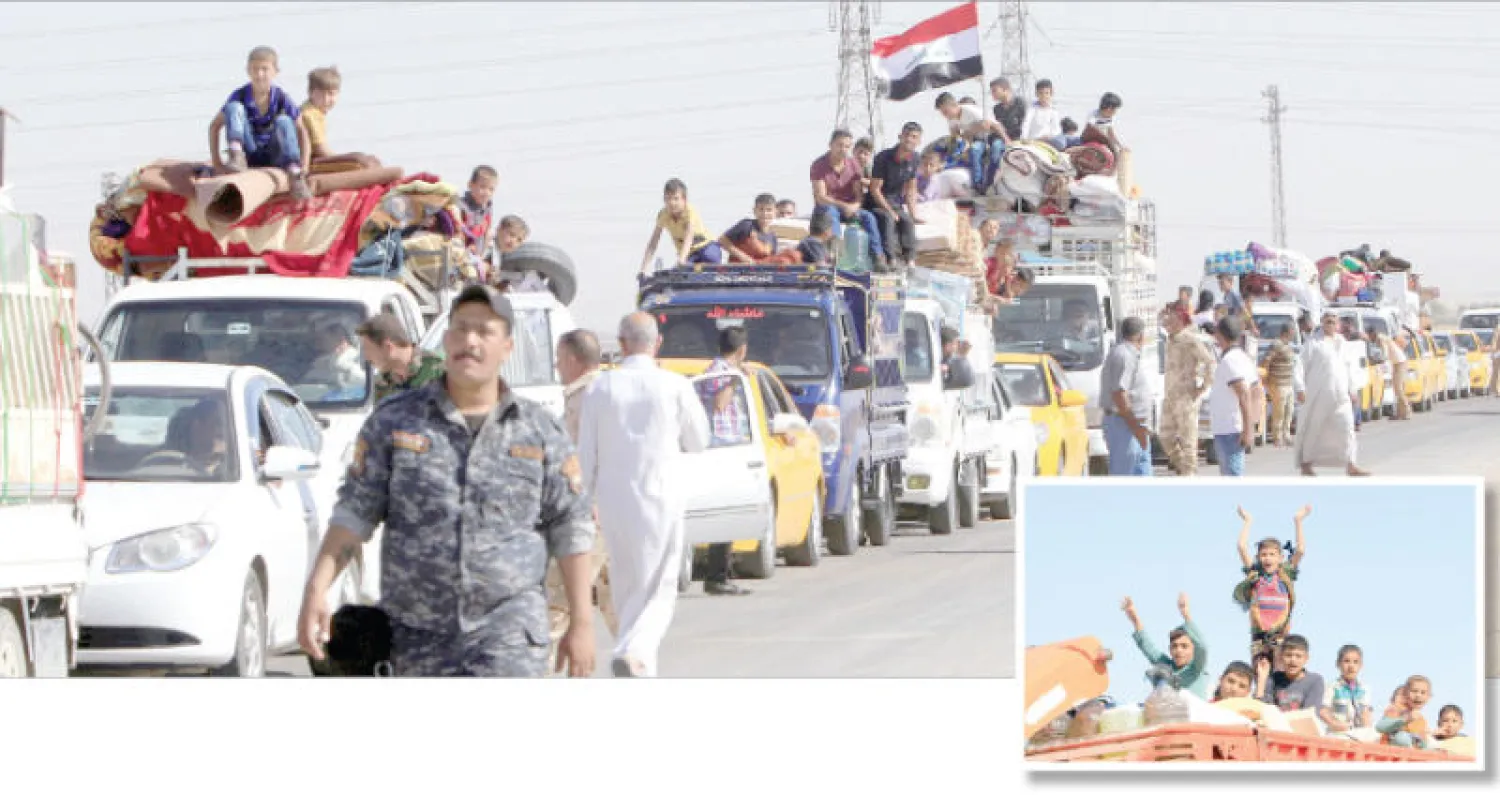 طابور من النازحين خلال عودتهم إلى الحويجة قرب كركوك أمس (رويترز) وفي الإطار، أطفال بين النازحين العائدين (رويترز)