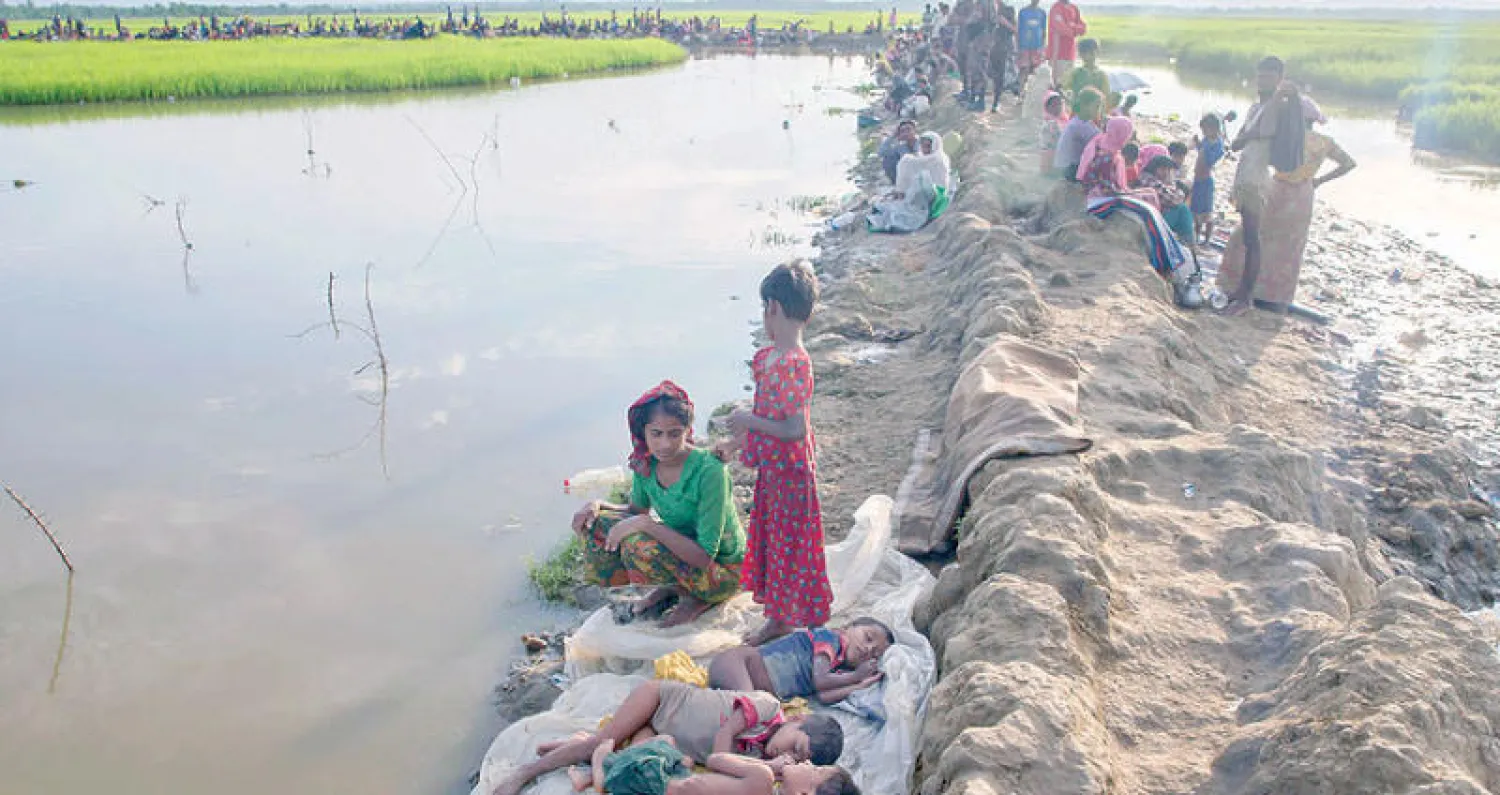 نازحون من الروهينغا يستريحون على ضفة نهر بعد وصولهم إلى بنغلاديش أمس (أ.ب)