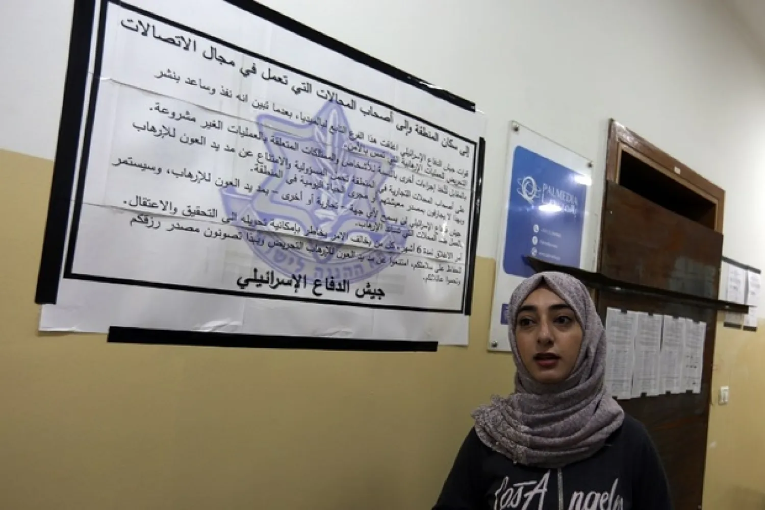 Employee of Palmedia reads poster placed by Israeli troops on doors of office in West Bank city of Nablus (AFP)