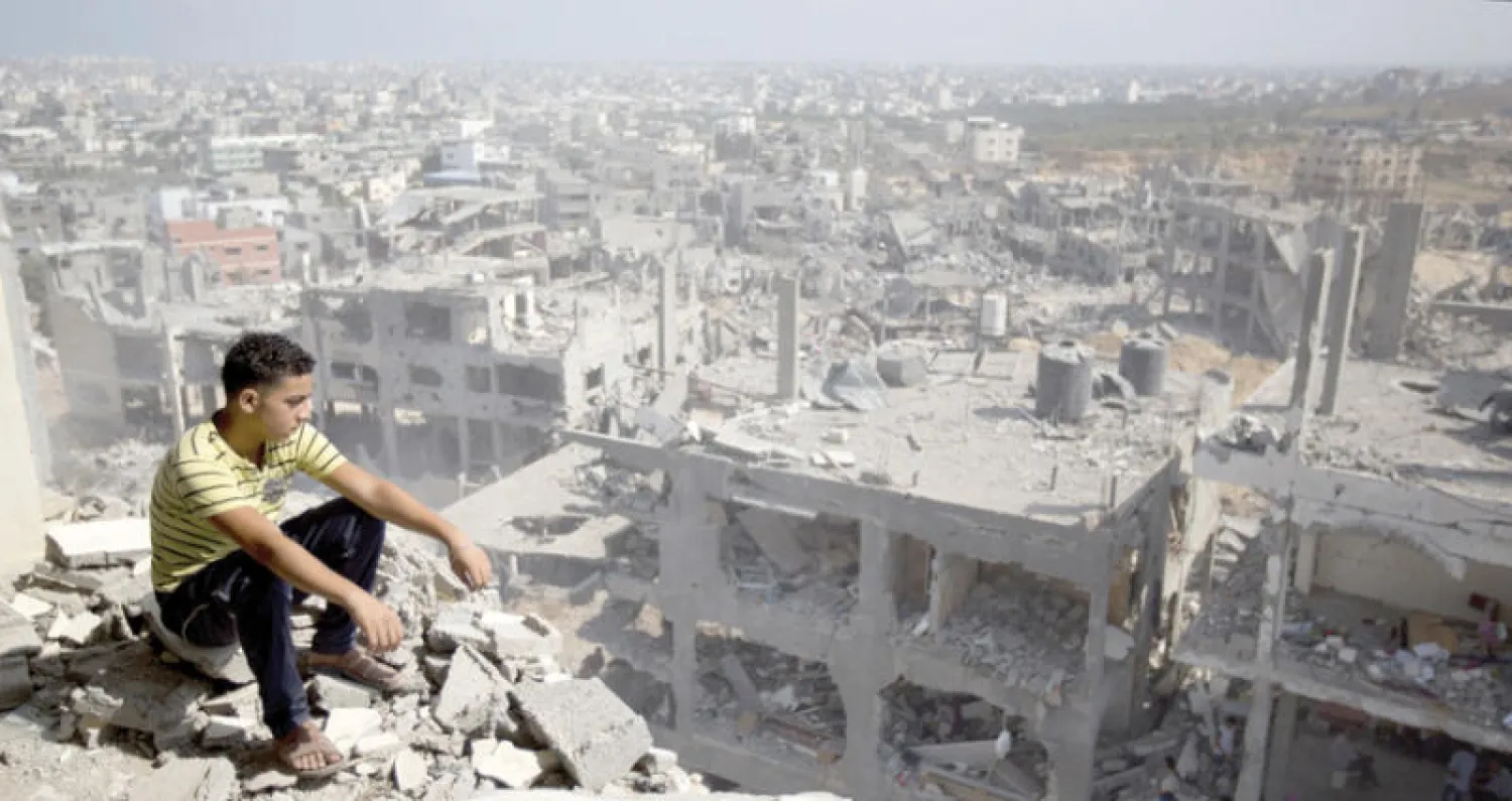 صورة أرشيفية تعود لعام 2014 لشاب فلسطيني يجلس على أنقاض مبنى مدمر في غزة (أ.ف.ب)