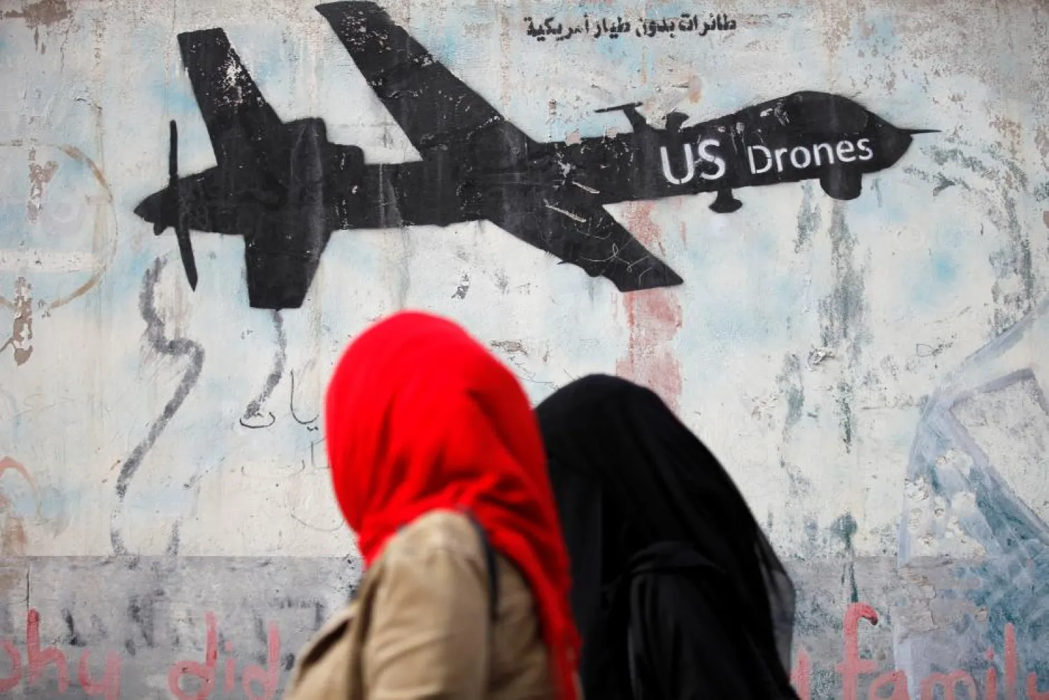 Women walk past a graffiti, denouncing strikes by US drones in Yemen, painted on a wall in Sana'a, Yemen February 6, 2017. REUTERS/Khaled Abdullah