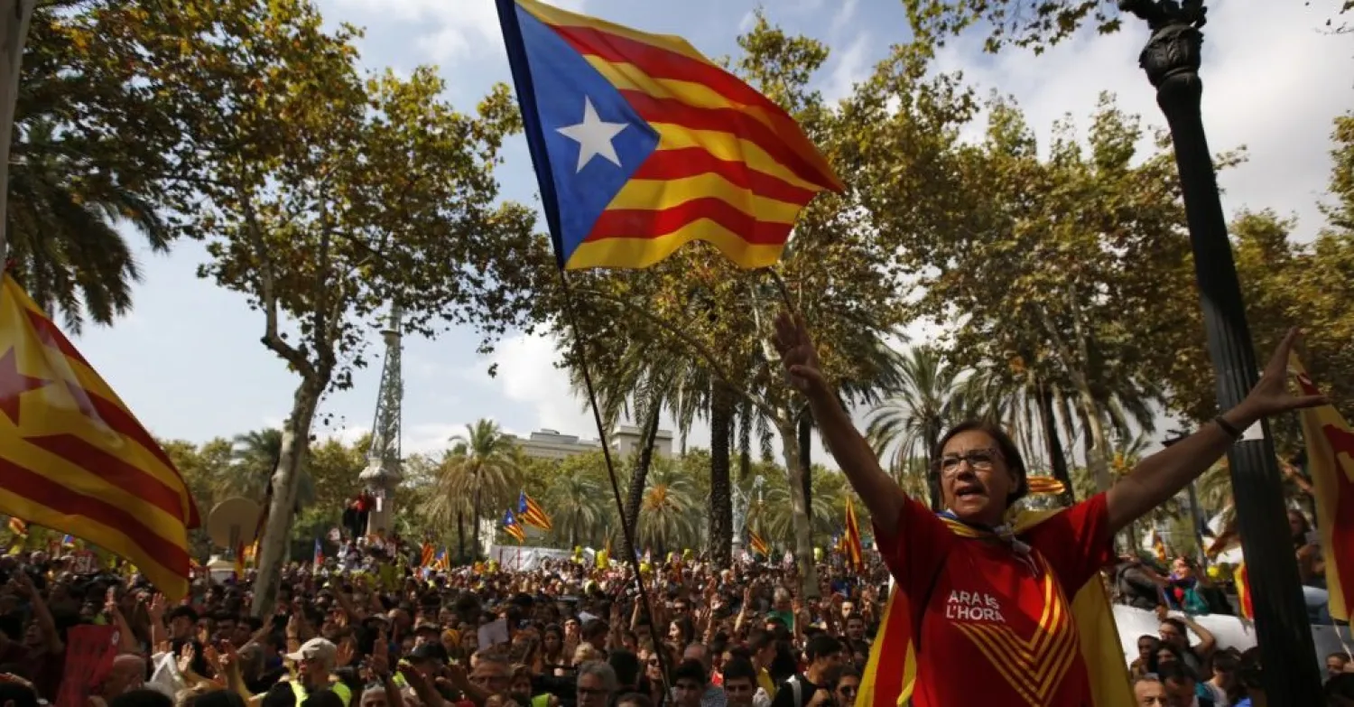 A woman gestures as others wave the ''estelada'' or Catalonia independence flags during a protest in Barcelona, Spain, Sept. 21, 2017. AP photo