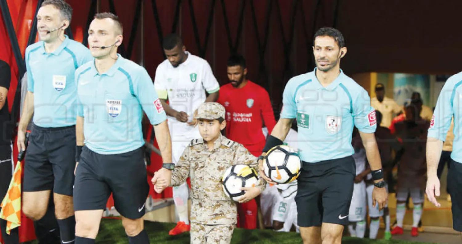 الطفل علي شويهي بصحبة حكام مباراة {الديربي} في طريقهم إلى الملعب (تصوير: سلمان مرزوقي)