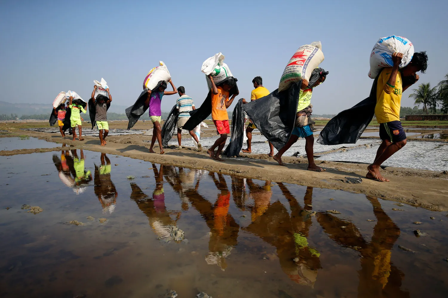 Rohingya refugee workers carrying bags of salt this month in a processing yard in Cox's Bazar, Bangladesh. REUTERS/Mohammad Ponir Hossain