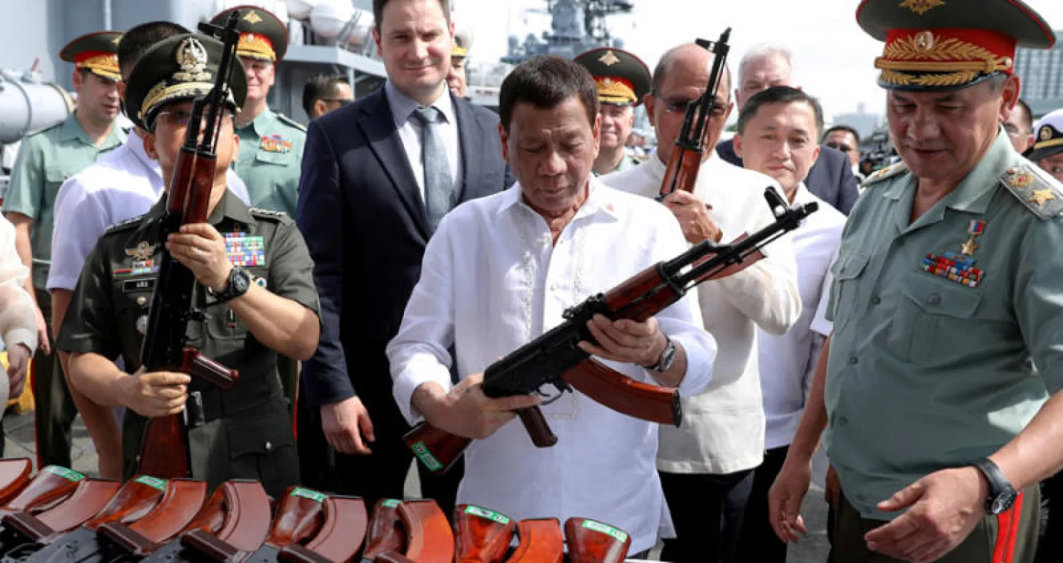 الرئيس الفلبيني رودريغو دوتيرتي ممسكاً ببندقية «إيه كي - 47» ضمن الأسلحة الروسية التي تسلمتها بلاده وإلى جواره وزير الدفاع الروسي سيرغي شويغو (رويترز)