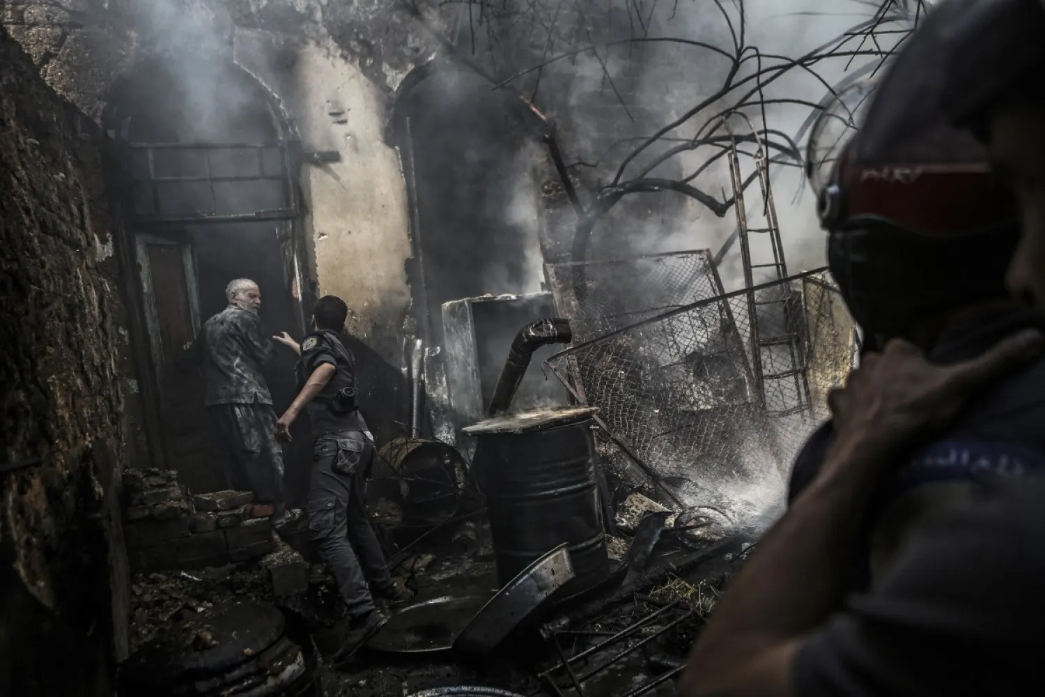 First-responders attempt to stop a man from entering his home following an airstrike in the rebel-held area of Douma, on the outskirts of Damascus, on Sept. 11, 2016. Mohammed Badra—EPA