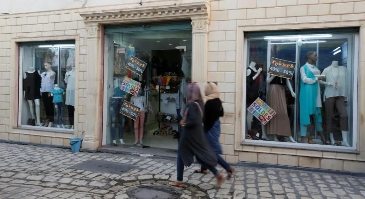  Women look at sale signs placed on a shop's windows while walking through central Mehdia,Tunisia, August 17, 2017. REUTERS/Zoubeir Souissi
