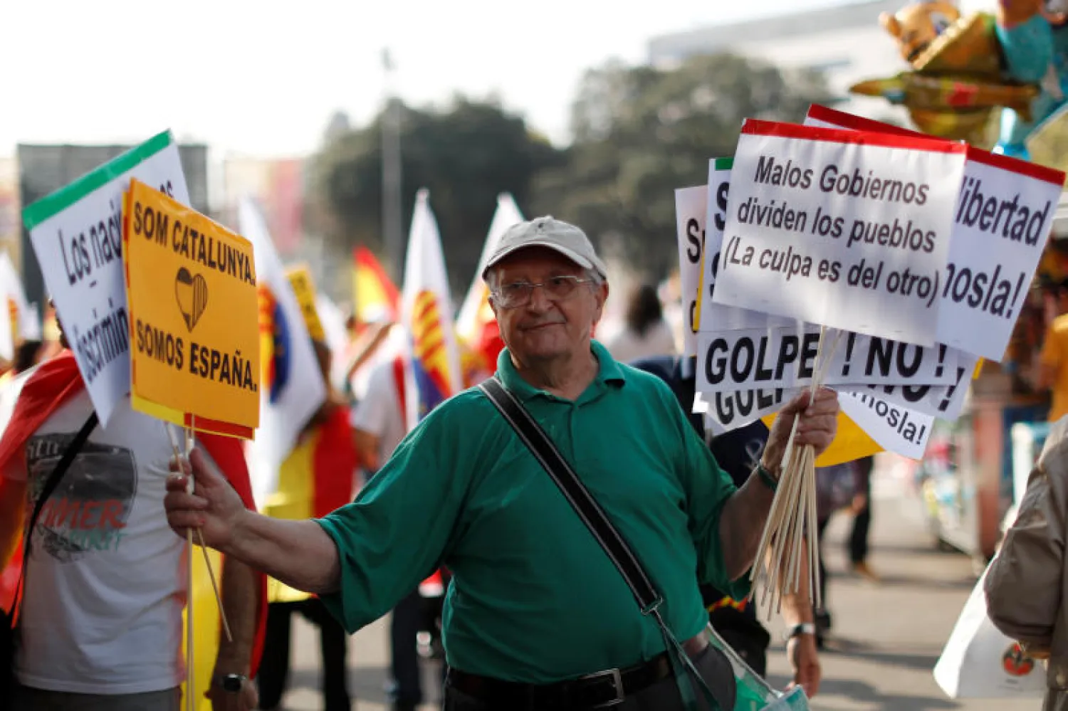 رجل يوزع لافتات كتب عليها «نحن كاتالونيا. نحن إسبانيا» خلال يوم إسبانيا الوطني في برشلونة (رويترز)