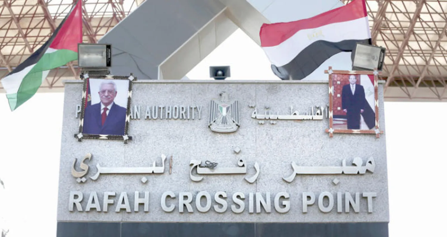 العلمان الفلسطيني والمصري وصور عباس والسيسي أعلى البوابة الرئيسية لمعبر رفح (أ.ب)