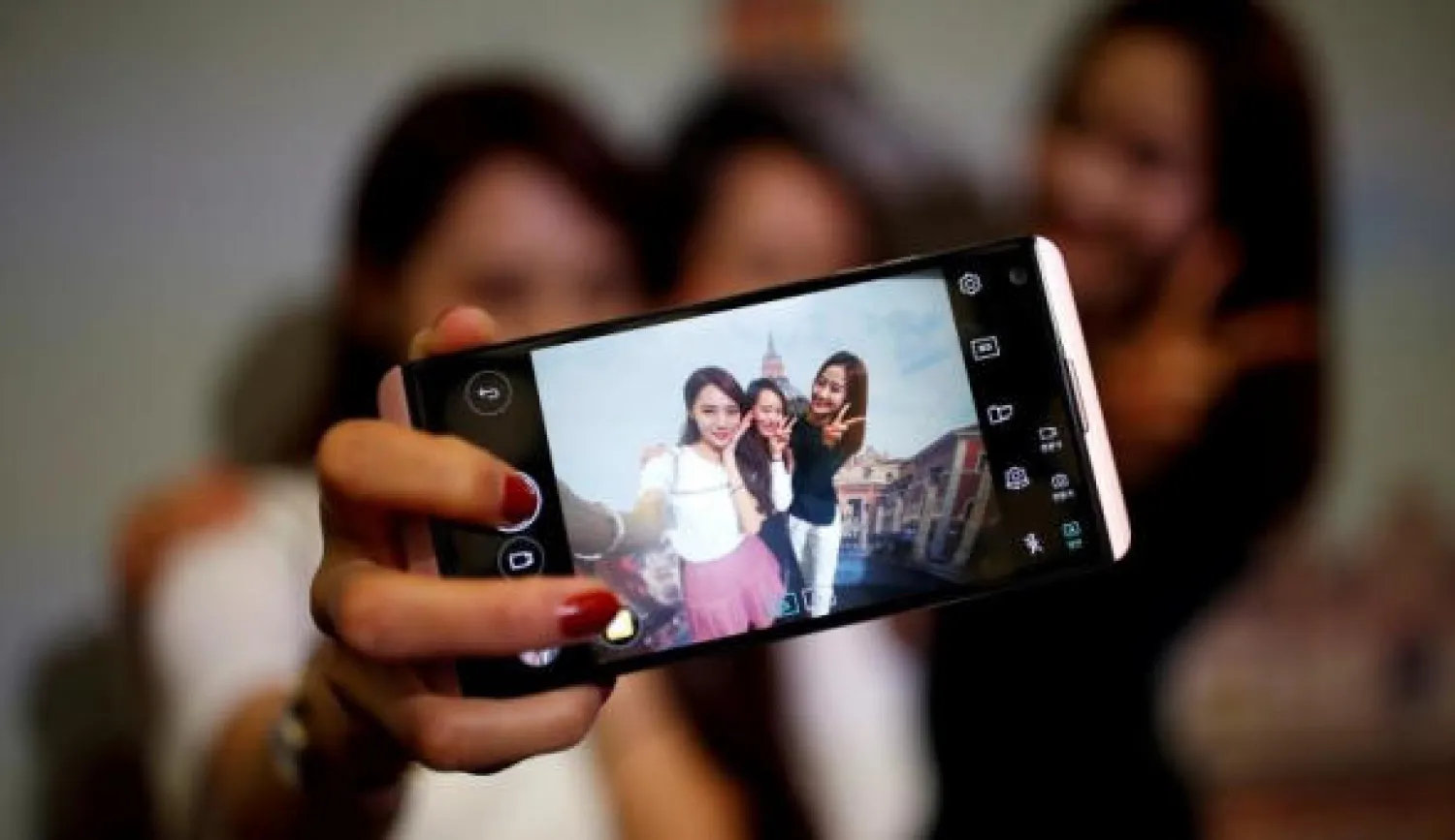 فتيات يلتقطن «سيلفي» باستخدام هاتف «إل جي»                   (رويترز)