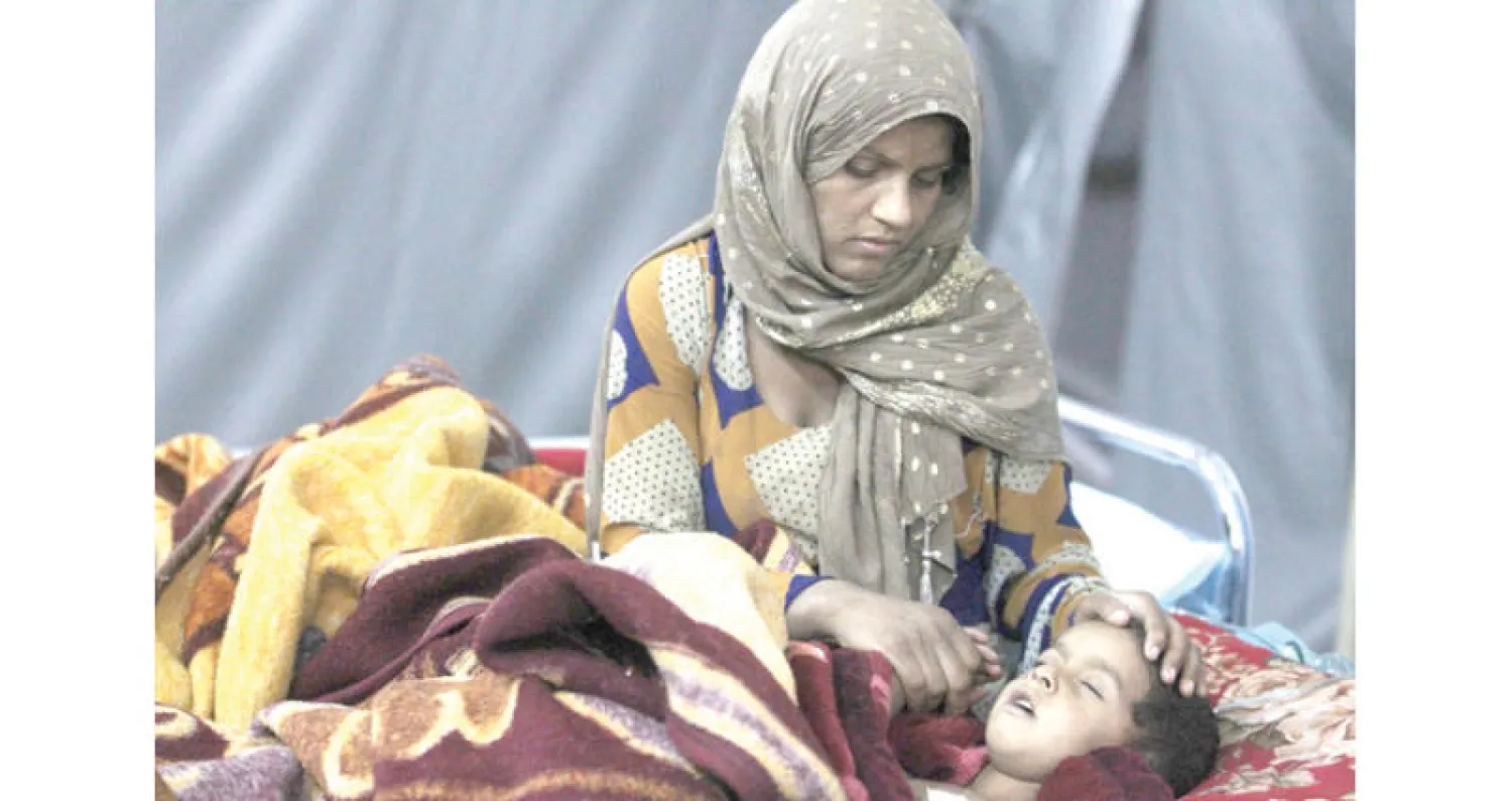 أم ترعى طفلها في مستشفى ميداني على أطراف القائم بعد إصابته في الاشتباكات بين القوات العراقية و«داعش» (أ.ف.ب)