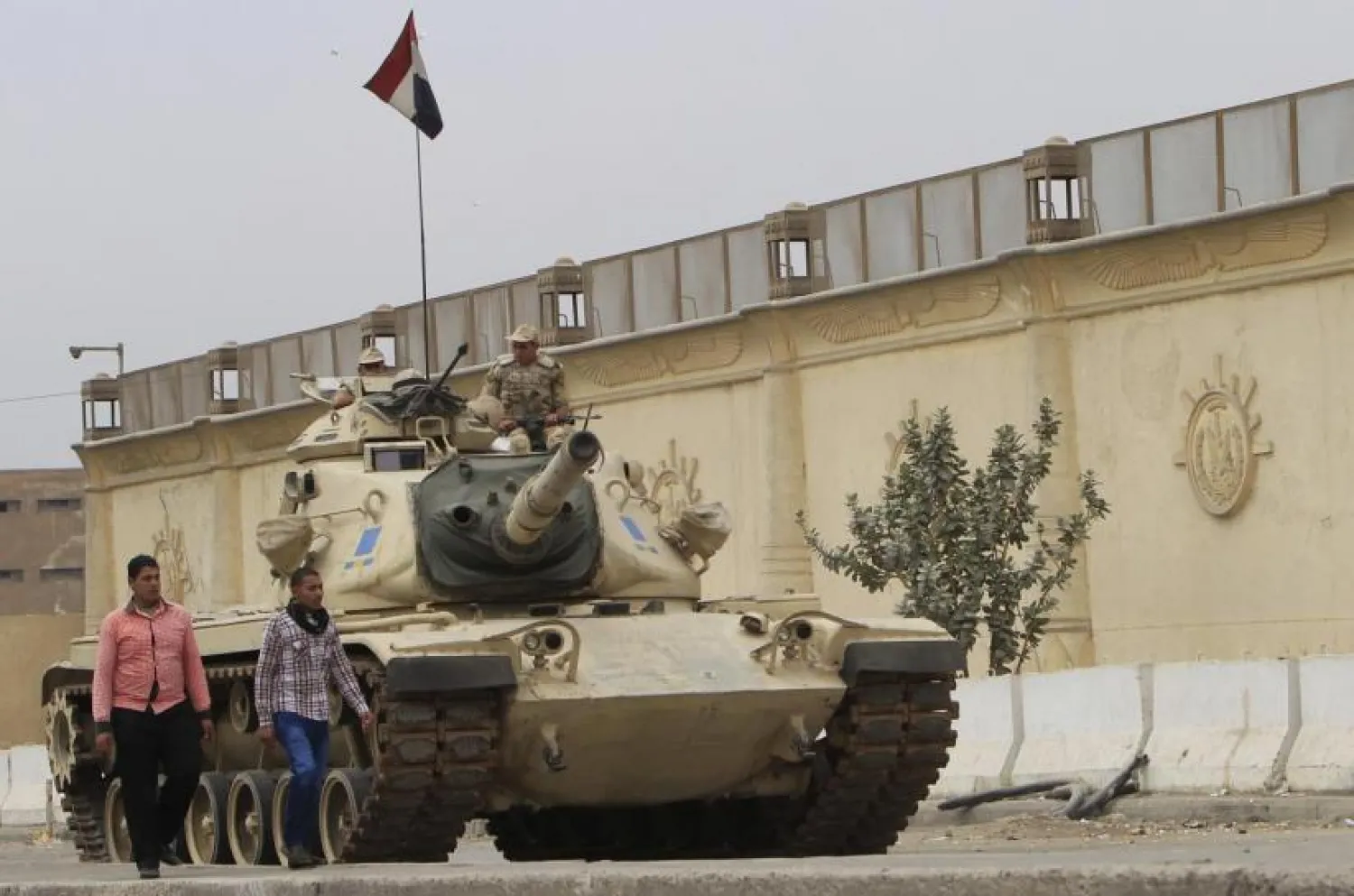 People walk past an Egyptian army tank positioned outside Cairo's Tora prison, March 23, 2014. REUTERS/Mohamed Abd El Ghany 