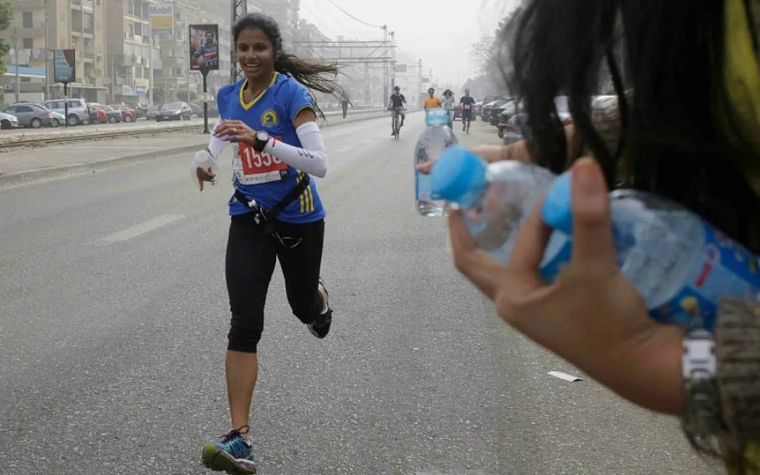 An Egyptian volunteer holds water bottles for passing runners participating in Cairo's annual Half Marathon in the Heliopolis district in Cairo, Egypt, Friday, April 17, 2015. (AP Photo/Amr Nabil)