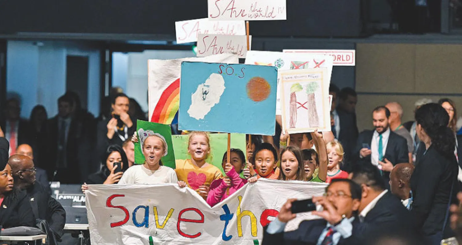 أطفال يحملون لافتات تدعو إلى إنقاذ العالم في افتتاح قمة المناخ الـ23 في بون أمس (أ.ب)
