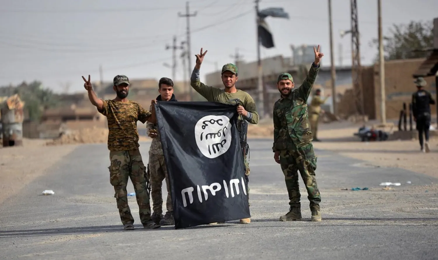 Popular Mobilization Forces fighters carry an ISIS flag downward after liberating the city of al-Qaim, Iraq November 3, 2017. (Reuters)