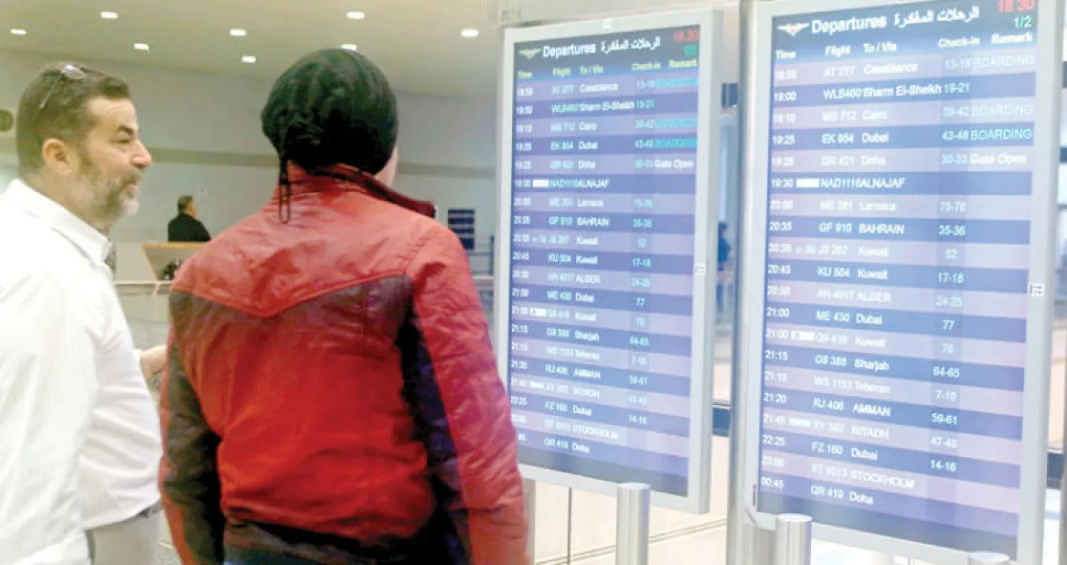 مسافرون يدققون في شاشة حركة الطائرات بمطار بيروت الدولي أمس (رويترز)