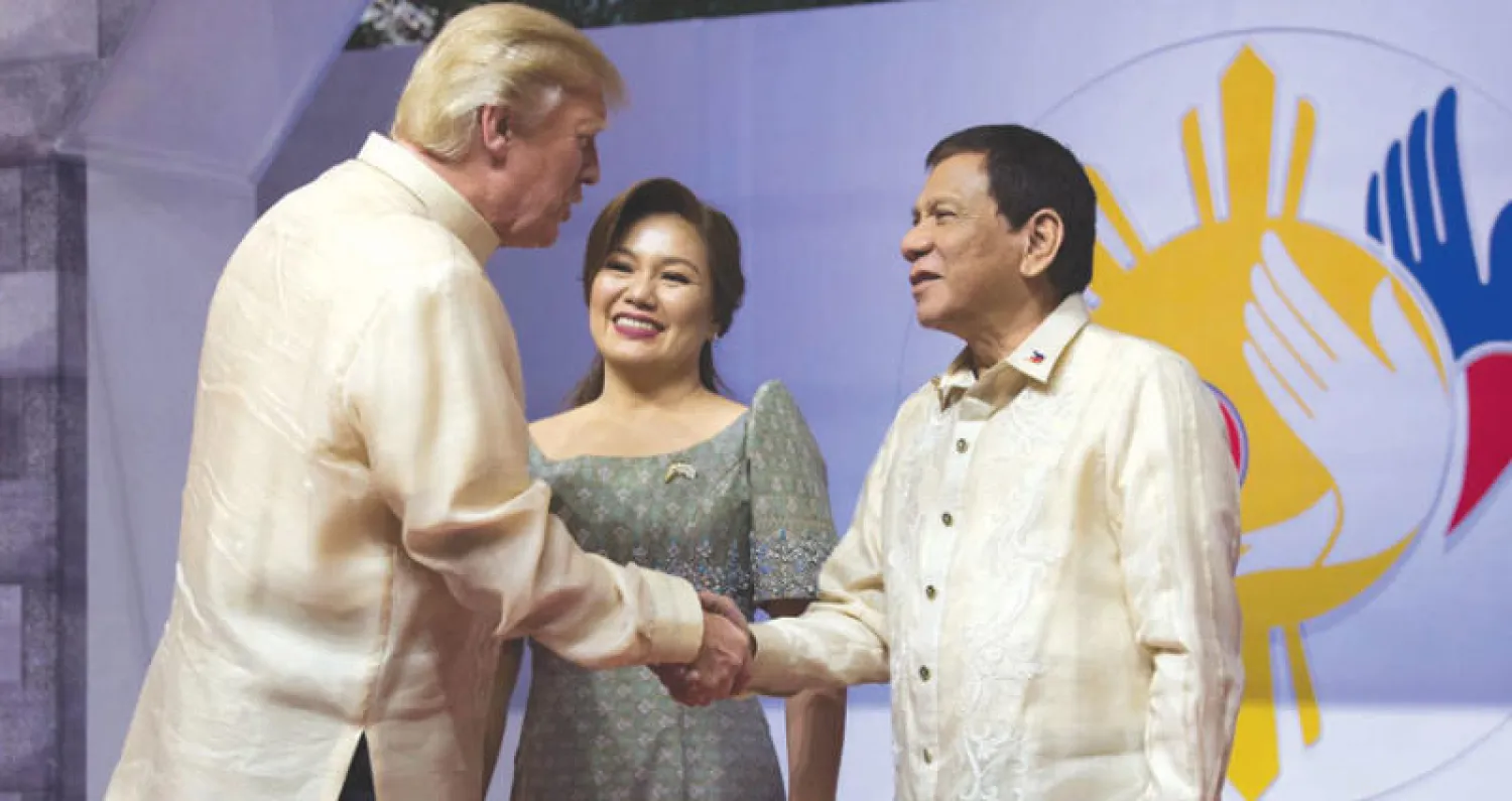 الرئيس الأميركي يصافح نظيره الفلبيني في مانيلا أمس (أ.ب)